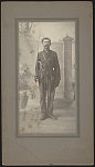 [Unidentified soldier in Confederate uniform and Maryland sword belt plate with cavalry saber, Sharps carbine, and handgun standing in front of painted backdrop showing stone wall]