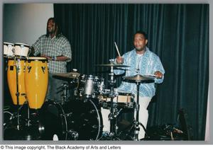 Photograph of two men playing their respective drums on stage