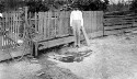 Unidentified man standing near a trough