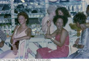 Photograph of a group of women, sitting in chairs next to a bar