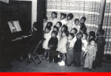 Mary Hata playing piano for singing children