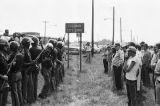 State troopers, Klansmen, and other white observers at the city limits of Cullman, Alabama, awaiting the arrival of a march organized by the Southern Christian Leadership Conference to protest the upcoming trial of Tommy Lee Hines.