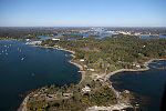 An October 2017 aerial view of New Castle, New Hampshire, with the historic seaport of Portsmouth, the largest city along the shortest coastline (18 miles) of any U.S. state, in the distance. The large white building with a red roof is the 1874 Wentworth-by-the-Sea Hotel, a historic grand resort hotel in New Castle. Now managed by Marriott, it is one of a handful of the state's surviving Gilded Age grand hotels, and the last located on the seacoast