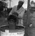 Woman filling a barrel with sugar cane juice at a syrup boil in Boyd, Alabama.