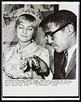 Singer Sammy Davis Jr. holds the hand of his bride, actress May Britt, showing the gold wedding band he gave her, for all to see The couple were married in private ceremonies at the negro singer's home 11/13.