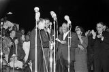 Martin Luther King Jr. shaking hands with a man, probably Father Paul J. Mullaney, at the "Stars for Freedom" rally at the City of St. Jude in Montgomery, Alabama, the night before the end of the Selma to Montgomery March.