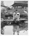 Three Japanese women in kimonos standing on bridge in Japanese garden