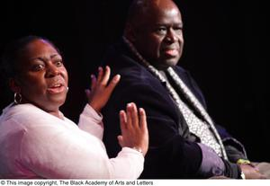 Performer and man sitting on stage