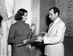 Myrna Loy holding African wood carvings