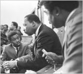 Martin Luther King, Jr., seated and speaking to a young man during a meeting at Maggie Street Baptist Church in Montgomery, Alabama.