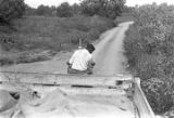 Man driving a tractor down a dirt road near Mount Meigs in Montgomery County, Alabama.