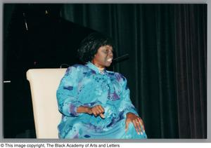 Photograph of Mzuri sitting in a chair, and clenching her left hand