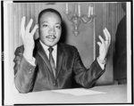 Thumbnail for [Rev. Martin Luther King, head-and-shoulders portrait, seated, facing front, hands extended upward, during a press conference]