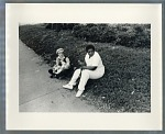 Two women seated at edge of sidewalk