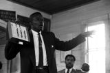 Willie Lee Wood, Sr., demonstrating a voting machine for an audience in a small wooden church building in Prattville, Alabama.