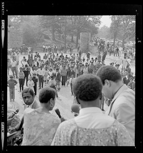 Group of speakers standing with microphones, addressing the crowd gathered at Franklin Park