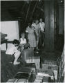 Maid, two workmen, and two other staff members packing books