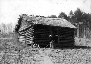 African-American man & woman in front of log house