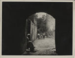 African-American children in housing courtyard. View through arched doorway with woman in foreground.