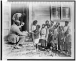 Teacher distributing fruit, sent to the Red Cross from Lake Wales, Florida, to African American school children outside school near Shaw, Mississippi]