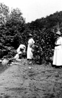 Two unidentified women, one man, and a little girl near a stream