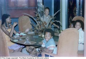 Photograph of a woman and four boys sitting at a dining table