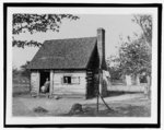 [Unidentified log dwelling, possibly for slaves or sharecroppers, with African American woman seated in doorway]