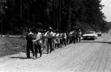 Edward Rudolph leading marchers down an unpaved road in Prattville, Alabama, during a demonstration sponsored by the Autauga County Improvement Association.