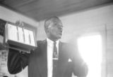 Willie Lee Wood, Sr., demonstrating a voting machine for an audience in a small wooden church building in Prattville, Alabama.