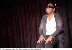 Performer speaking on stage wearing sunglasses