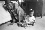 Percy Jones, Jr., kneeling on the floor with his daughter Barbara beside a bed in his home on Clayton Alley in Montgomery, Alabama.