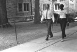 Two men conversing while walking on sidewalk at Duke University.