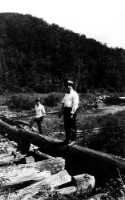 Two unidentified men standing on a log