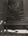 Two African American men loading used tires on a boxcar.