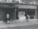 Men with dog survey damaged storefront on Clinton Avenue North after riot, Rochester, NY, 1964