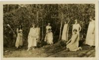 Individuals Posed Near Trees with Costumes and Head Wreaths