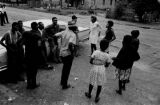 Roosevelt Barnett, Richard Boone, Lula Williams, and others, standing in the dirt lot in front of Pugh's Superette on Foster Street in Newtown, a neighborhood in Montgomery, Alabama.