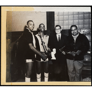 Two Boys' Club members pose with Richard B. K. McLanathan, at center, and an unidentified man, holding their basketball tournament trophy