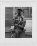 [Lower West Side, Buffalo, N.Y. Samuel P. "Pee Wee" West, African-American, three-quarter length portrait, facing front, seated on large crate, with store in the background]