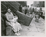 Thumbnail for Woman with a baby sitting outside of building from which they had been evicted, in Harlem, New York