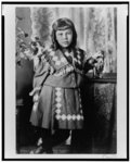 [African American girl, full-length portrait, standing next to table, facing front]