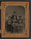 [Blacksmith Thomas Nevins and Captain Lester D. Wilson of Co. F, 75th New York Infantry Regiment, and unidentified soldier, who re-enlisted in Hancock's First Veterans Corps, drinking wine and smoking cigars in front of painted backdrop showing palm tree and tents]