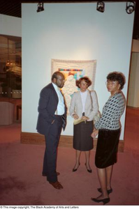 Photograph of three guests standing in front of quilted artwork