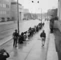 Fred Shuttlesworth and other civil rights demonstrators kneeling before a police officer during a protest march in downtown Birmingham, Alabama.