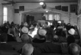 Norman Lumpkin speaking to an audience in a small wooden church building in Prattville, Alabama, probably during a meeting of the Autauga County Voters Association.