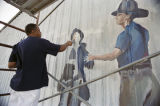 Lorenzo Green painting a firefighter for a patriotic mural on the side of Lambert's Cafe on Highway 59 in Foley, Alabama.