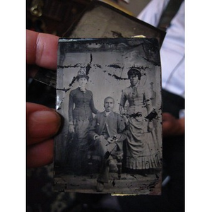 Two African American women standing next to a seated African American man