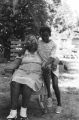 Blues Singers: Lake Mary, Miss. Scott Dunbar playing guitar outside on porch, Martha Dunbar and granddaughter seated outside, interior of Dunbar home (BSP I-68 #130)