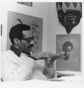 Maxwell L. Roach sitting at desk, talking