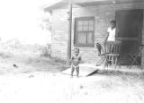 Baby standing in the yard in front of a brick house in Newtown, a neighborhood in Montgomery, Alabama.